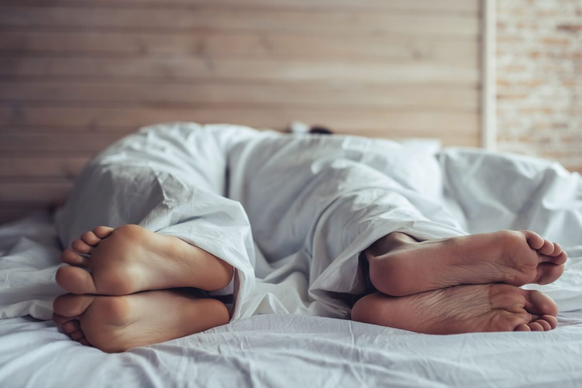 Couple-lying-on-white-bed-feet-scaled